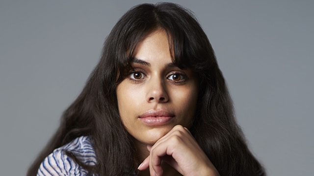 Ashani Lewis a woman with long brown hair and brown eyes stares into the camera